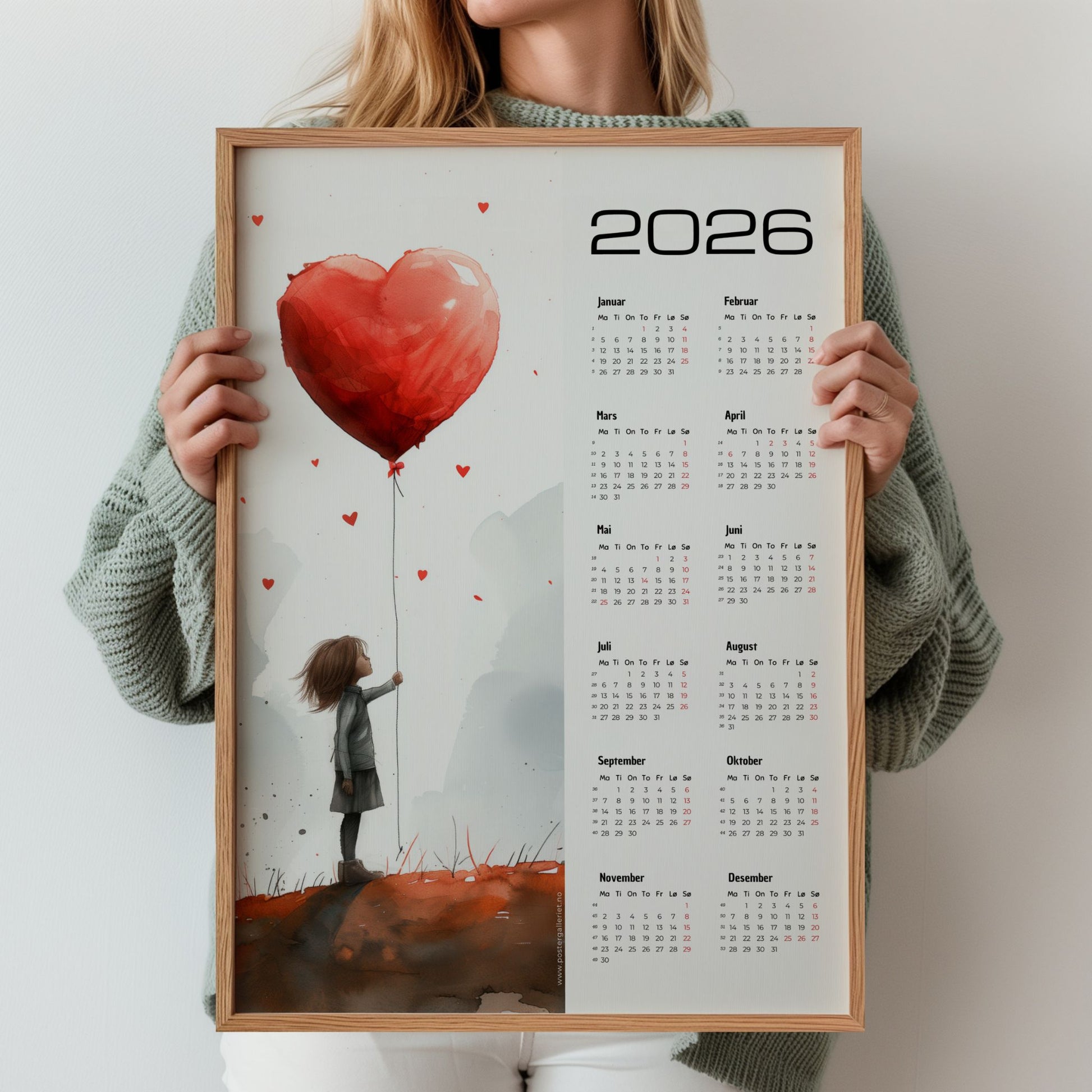 Kalender 2026 med akvarellmotiv av jente med hjerteformet ballong og oversiktlig kalenderdel. Illustrasjon viser kalender i eik ramme.