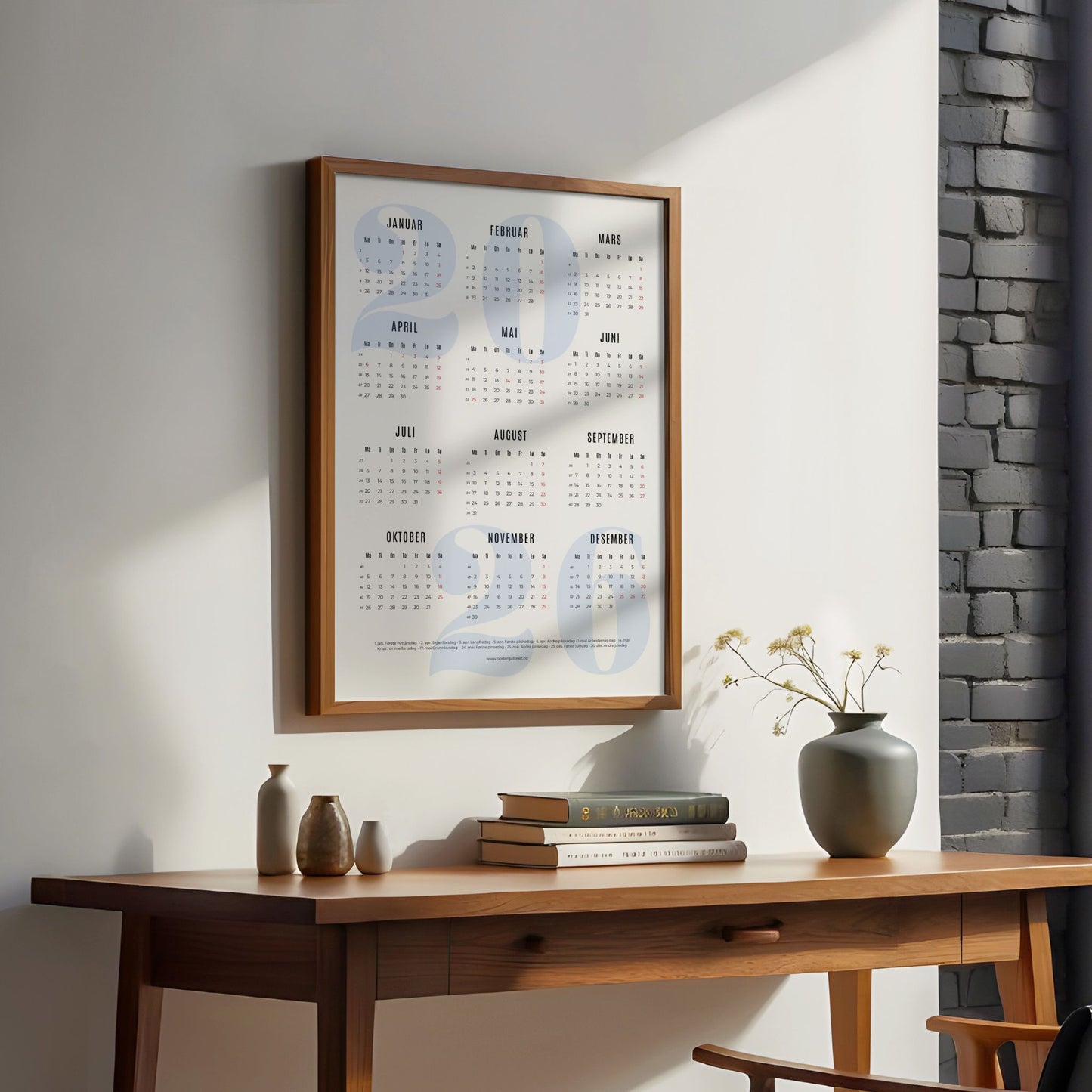 Minimalistisk årskalender 2026 med stort, lyst blått årstall i bakgrunnen og ryddig oversikt over månedene. illustrasjon viser kalender med blått årstal i eik ramme ved et skrivebord.