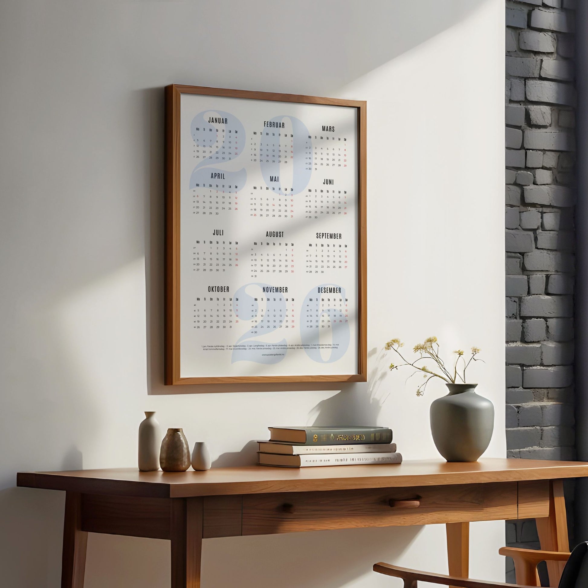 Minimalistisk årskalender 2026 med stort, lyst blått årstall i bakgrunnen og ryddig oversikt over månedene. illustrasjon viser kalender med blått årstal i eik ramme ved et skrivebord.