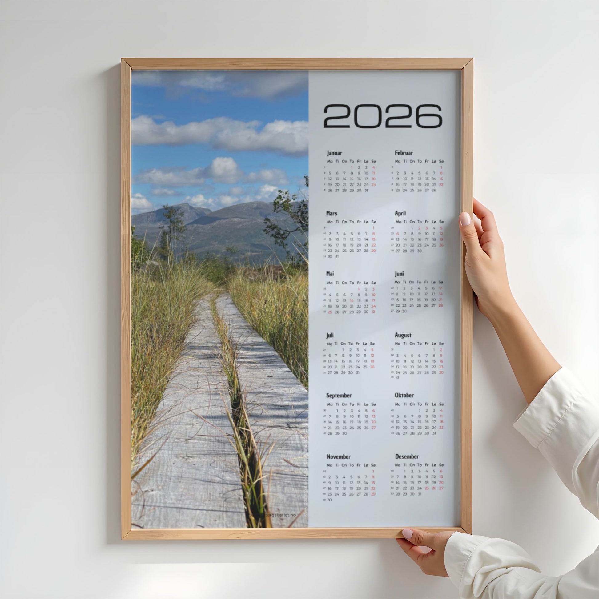 Kalender 2026 med foto av en plankesti som leder inn i fjellandskapet. Illustrasjon viser kalender i eik ramme.