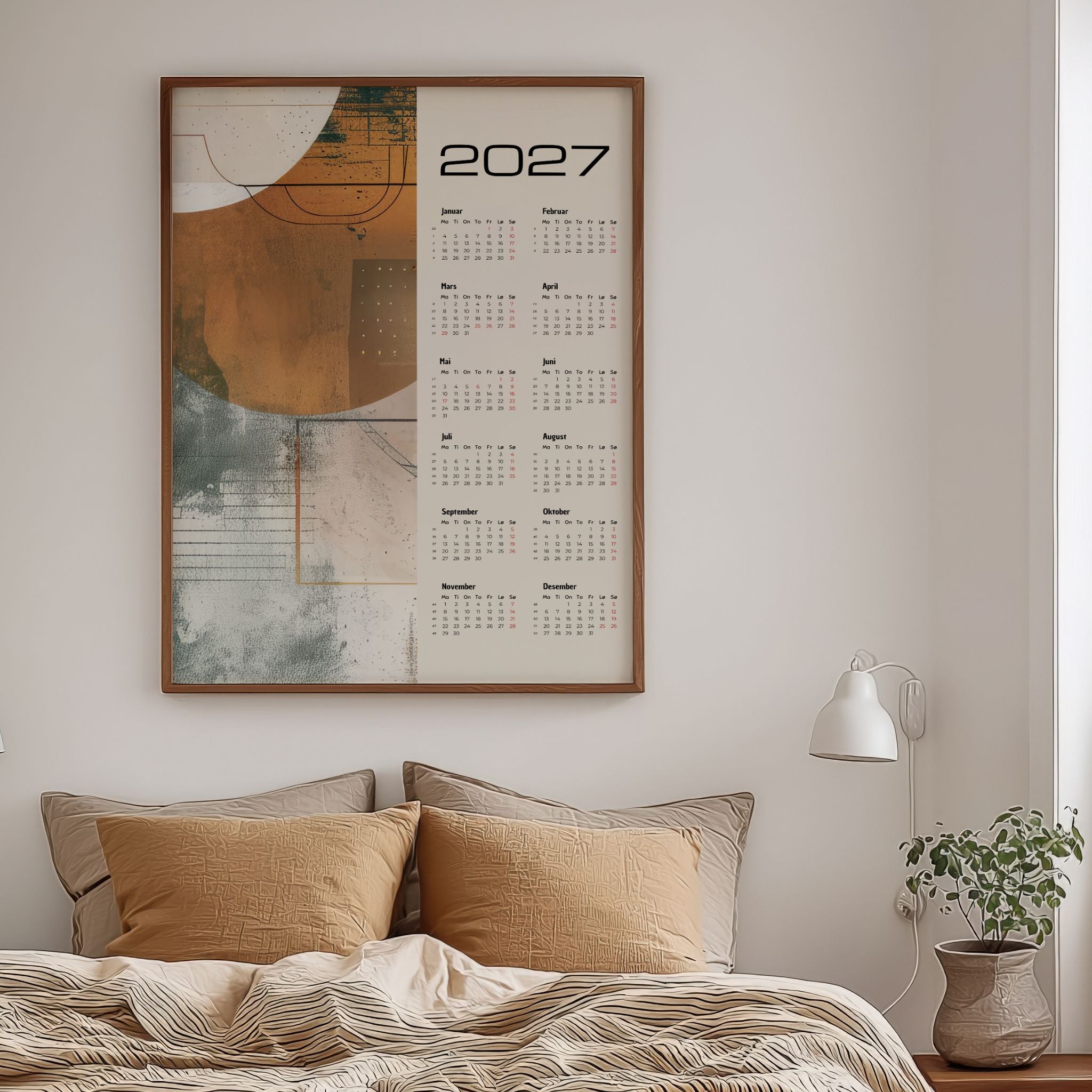 Grafisk kalender 2027 med abstrakt motiv i varme jordtoner, vist på vegg over seng