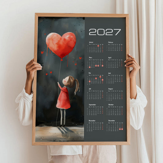 Kalender 2027 med pike, rød hjerteballong og mørk bakgrunn, holdt i eikeramme.