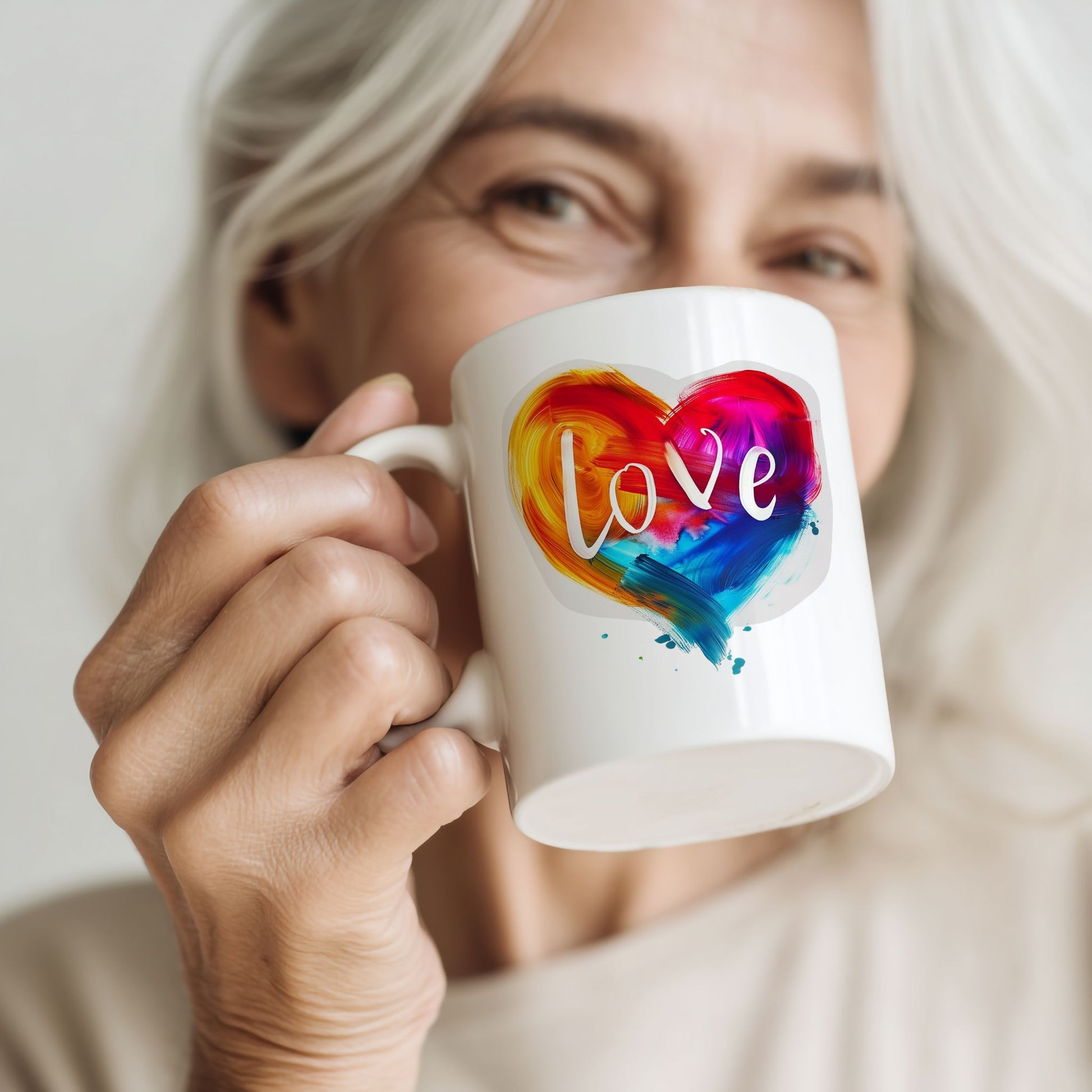 Kvinne holder Love in Color krus med fargerikt hjertemotiv og teksten Love.