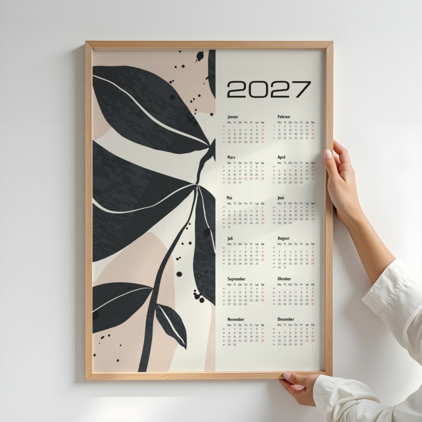 Monochrome Botanica kalender 2027 holdt opp for å vise størrelse og botanisk design