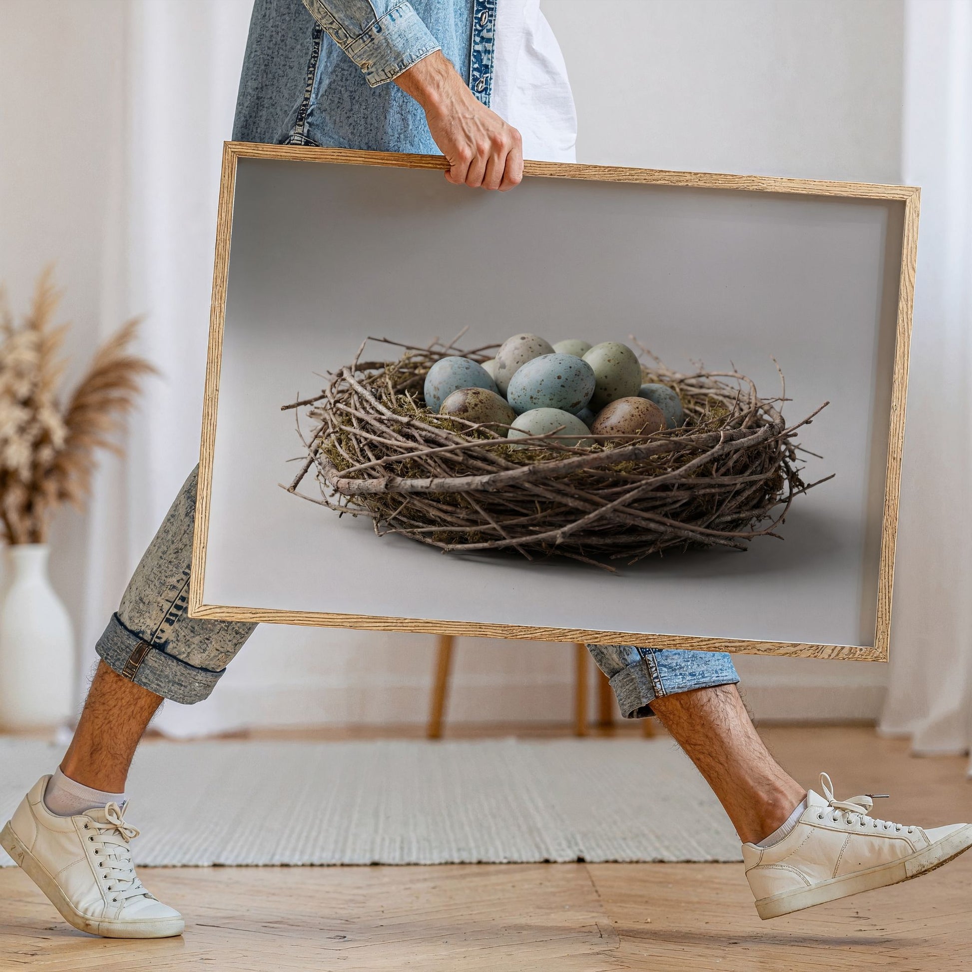 Minimalistisk påskeplakat med rede og egg i treramme holdt i hånd