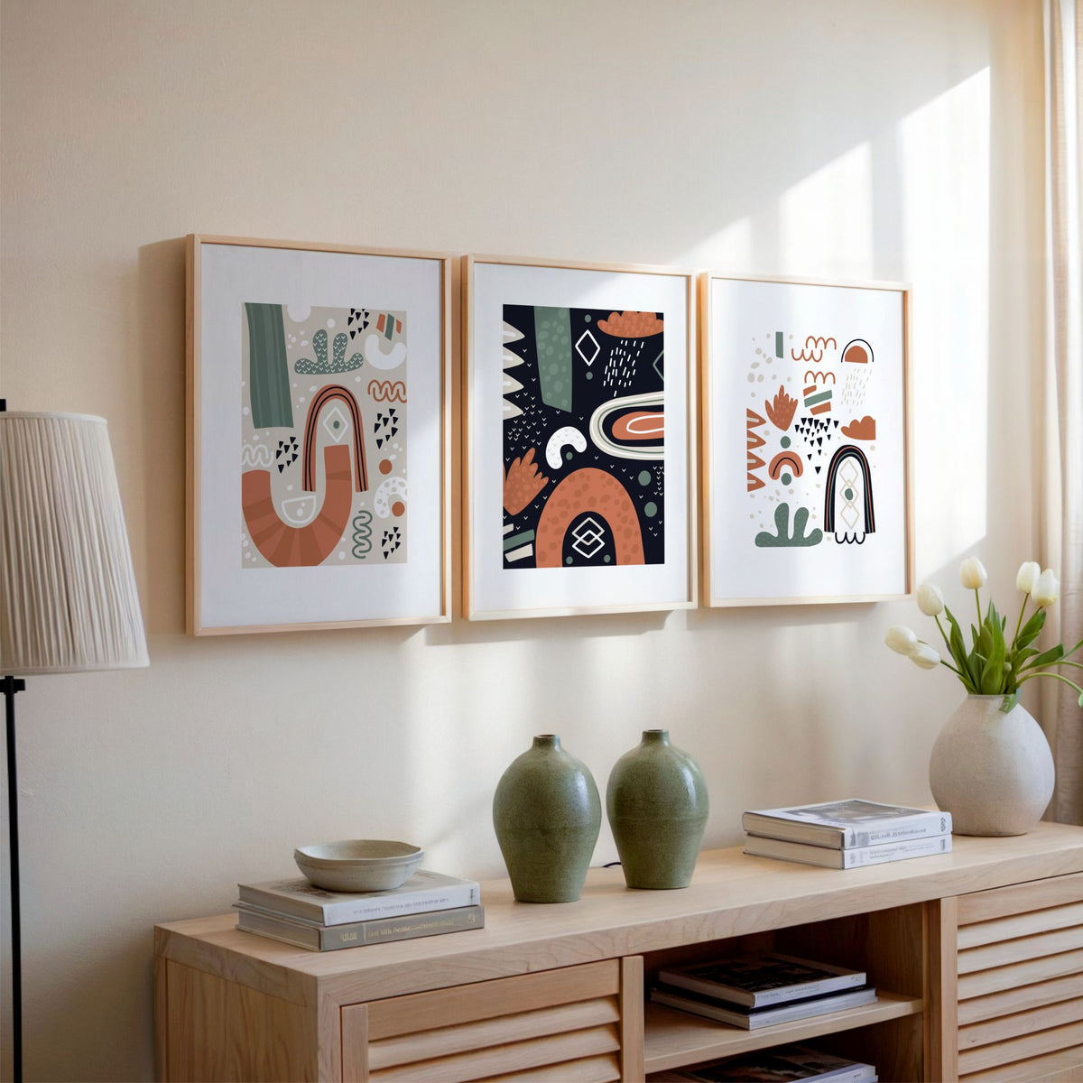 Tre grafiske plakater fra Nordic Abstractions Trio i lyse trerammer over skjenk