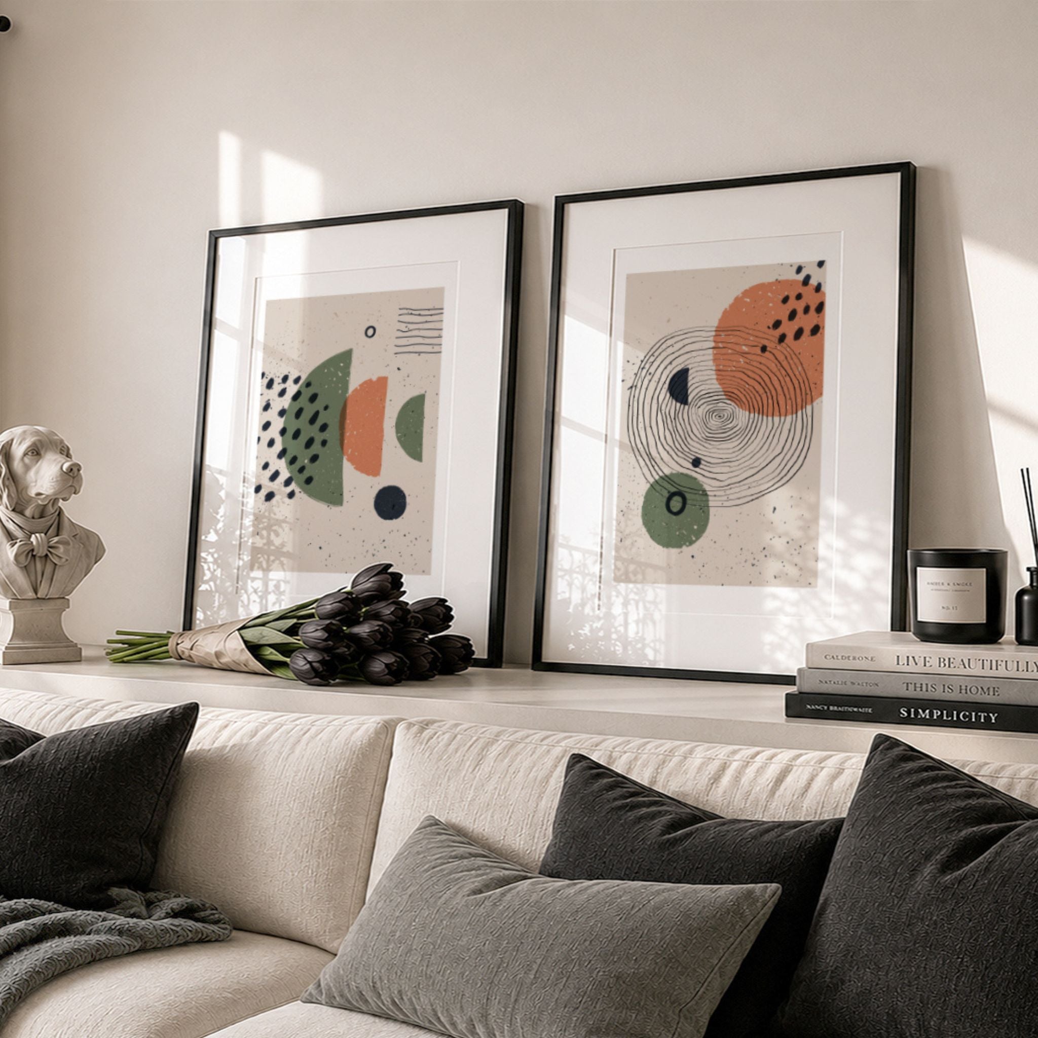 To plakater fra Organic Rhythm Collection i sorte rammer over lys sofa