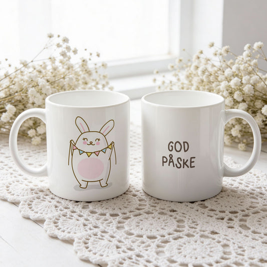 Hvitt keramikkrus med søt påskehare som holder vimpelrekke og teksten God påske på motsatt side.