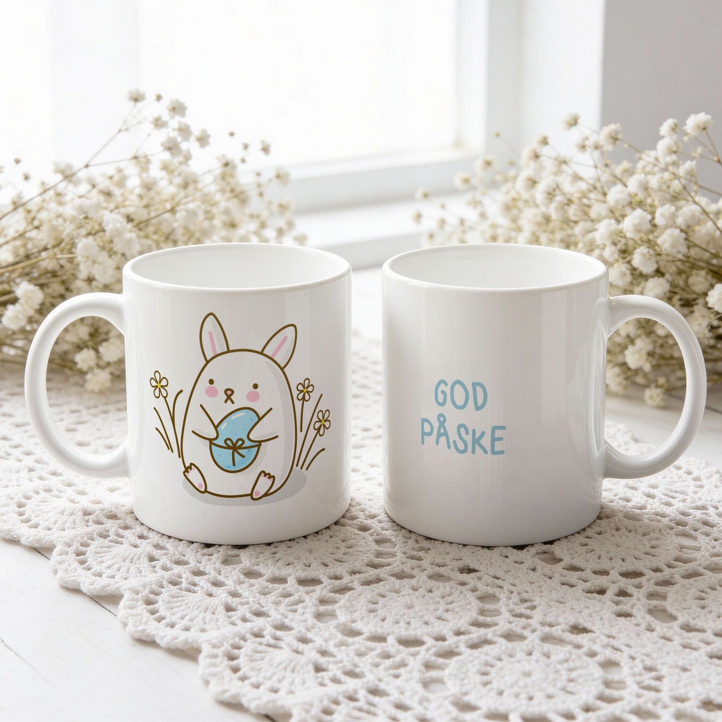 Hvitt keramikkrus med søt påskehare som holder lyseblått påskeegg og teksten God påske i blå tone på motsatt side.