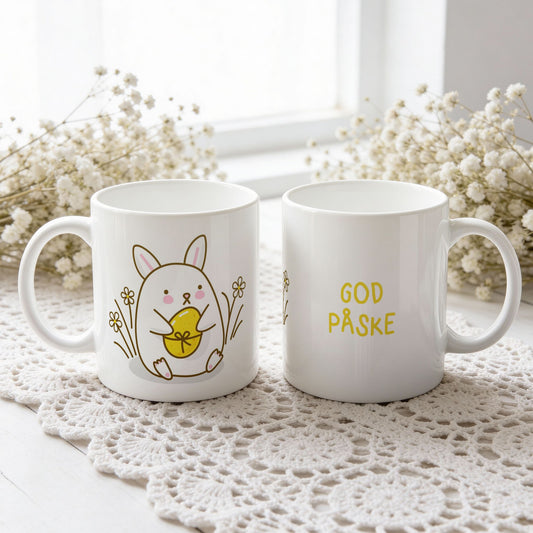 Hvitt keramikkrus med søt påskehare som holder gult påskeegg og teksten God påske på motsatt side.
