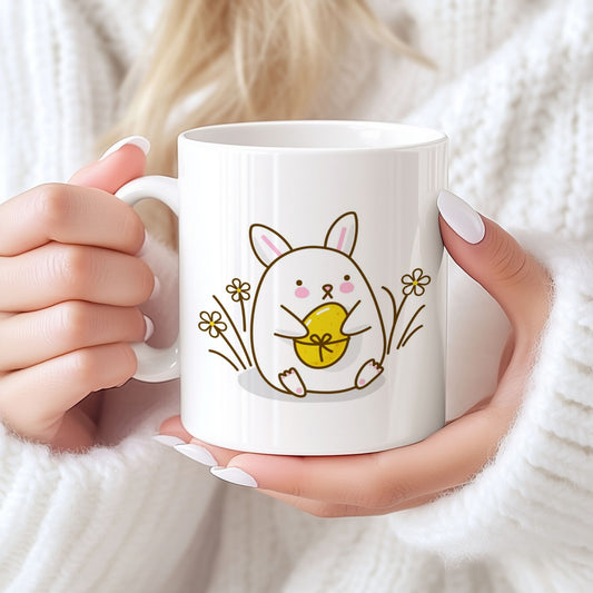 Hvitt keramikkrus med søt påskehare som holder gult påskeegg og teksten God påske på motsatt side. Kvinne holder krus.