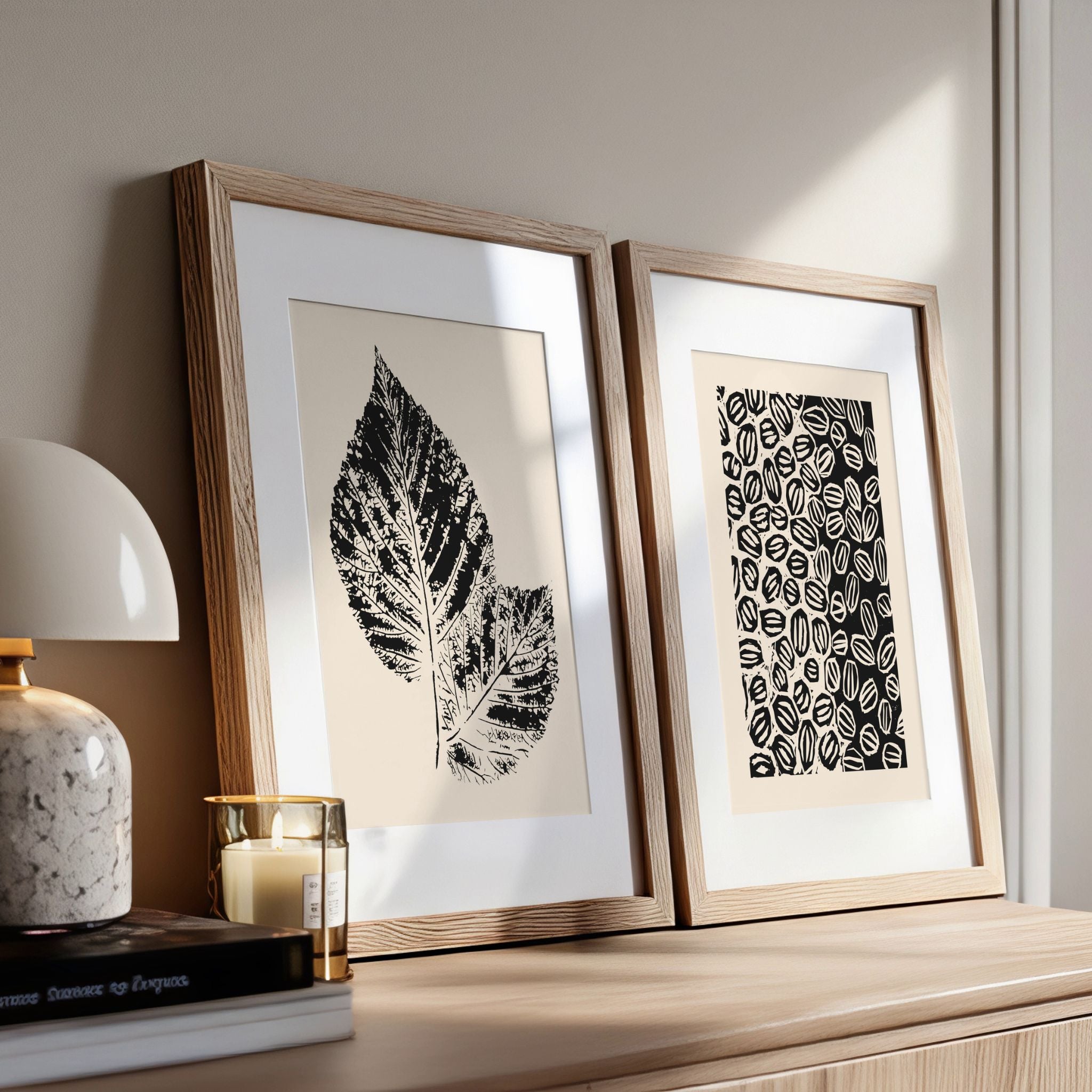 Grafisk plakatduo fra Soft Balance Collection lent mot kommode i lyst interiør.