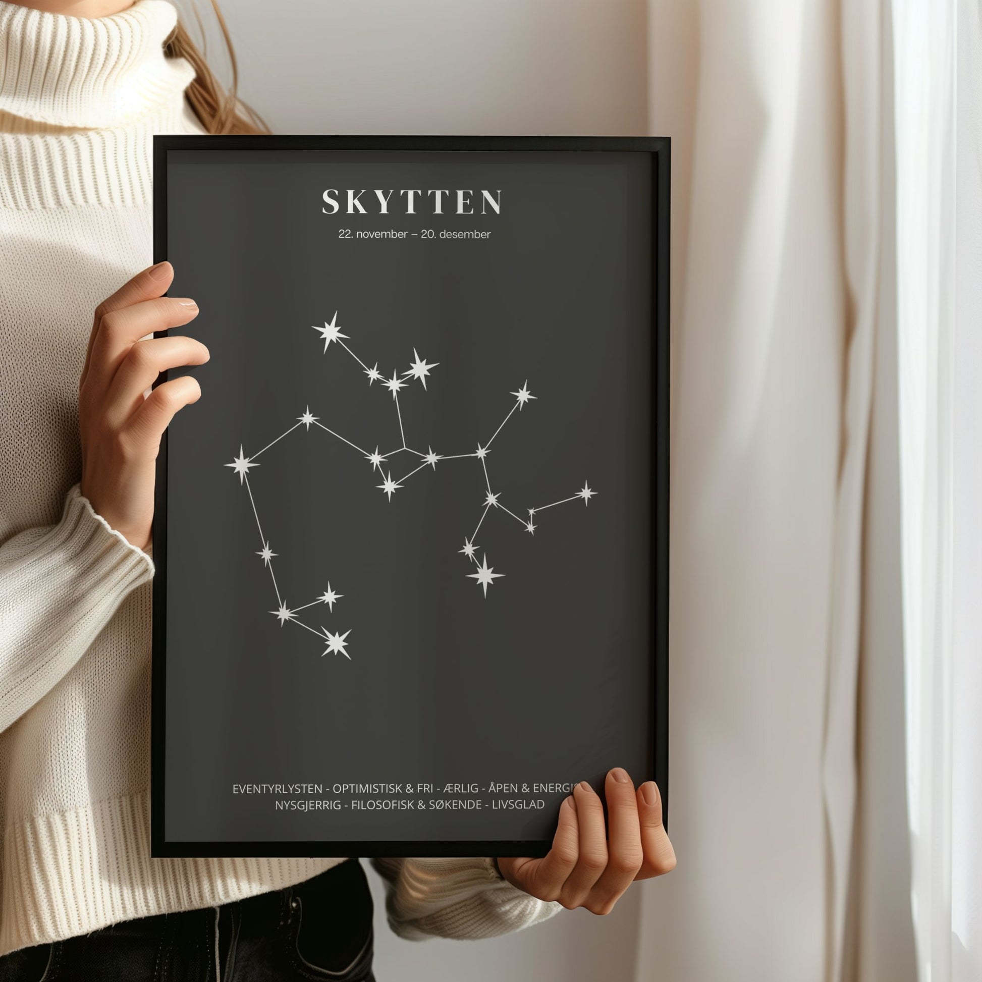 Minimalistisk stjernetegnplakat med stjernebildet Skytten i hvitt på sort bakgrunn. Person som holder ramme.