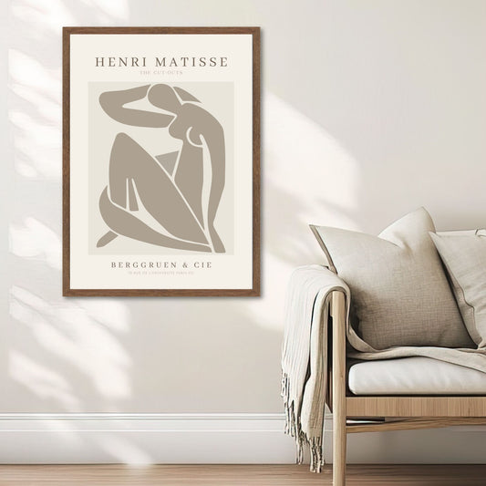 The Cut-Out Muse – Matisse-inspirert kunstplakat. Illustrasjon viser plakat i valnøtt ramme ved en sofa.