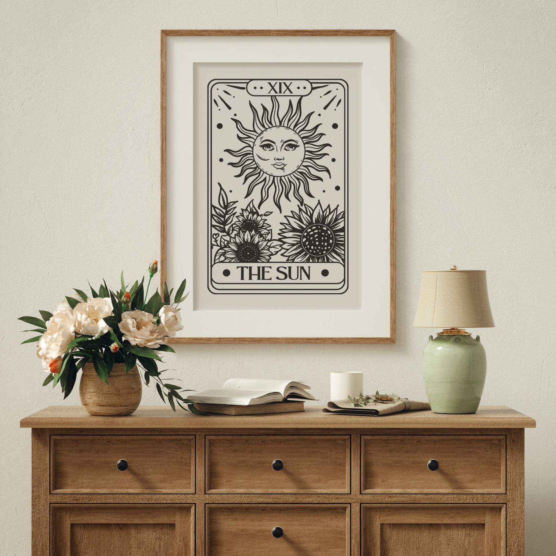 Svart/hvit kunstplakat med stilisert solmotiv inspirert av tarotkort. Illustrasjon viser plakat med passepartout i eik ramme over en komode.