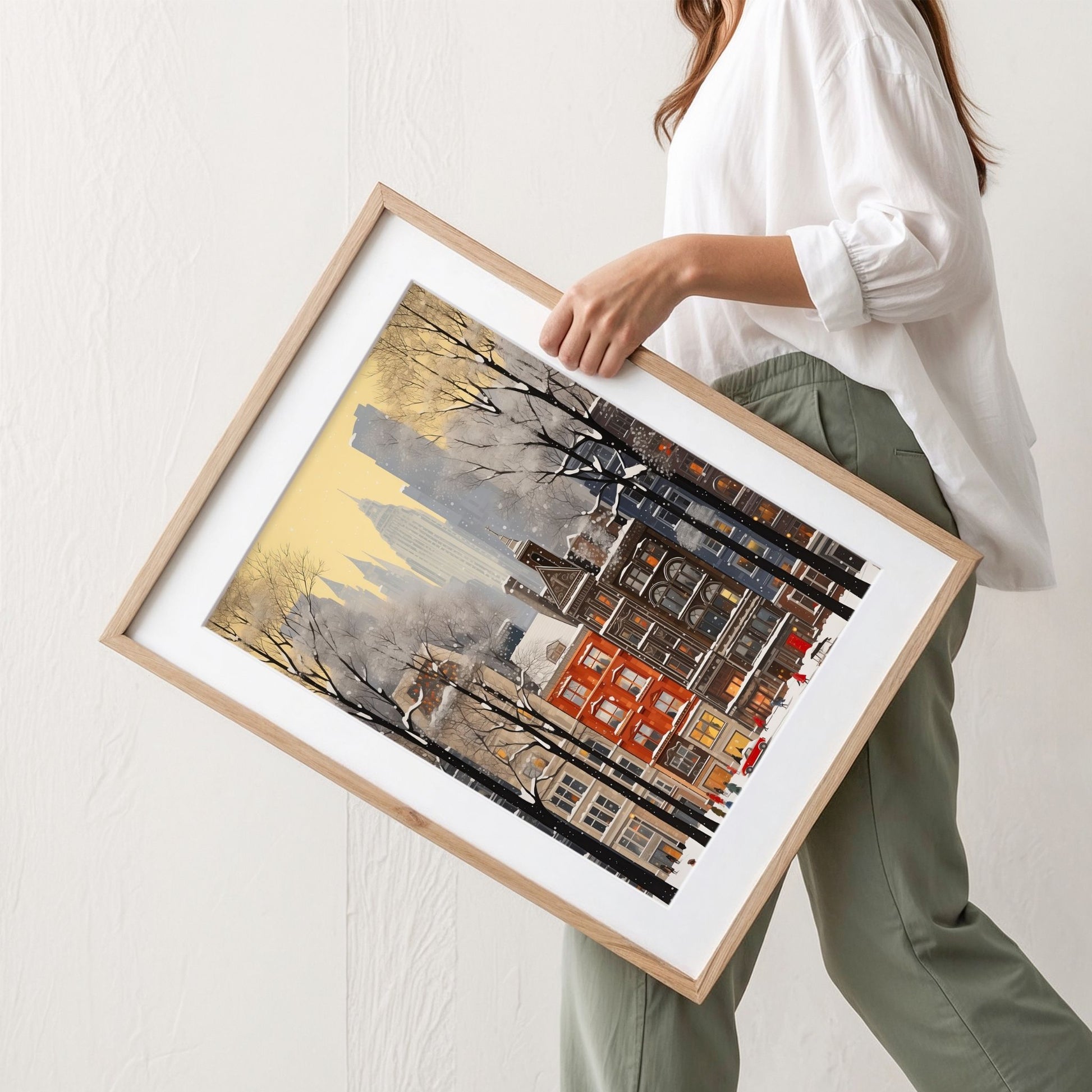 Vinter i Storbyen plakat med snødekt bylandskap, høye bygg og varme lys i vinduene. Illustrasjon viser plakat med passepartout i eik ramme.