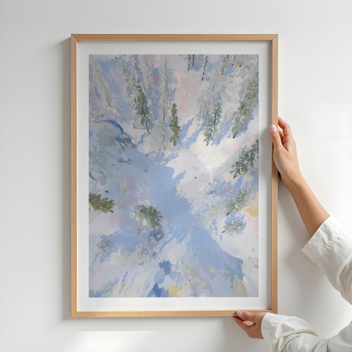 Winter Stillness vinterplakat i eikeramme med hvit passepartout holdt opp av en person