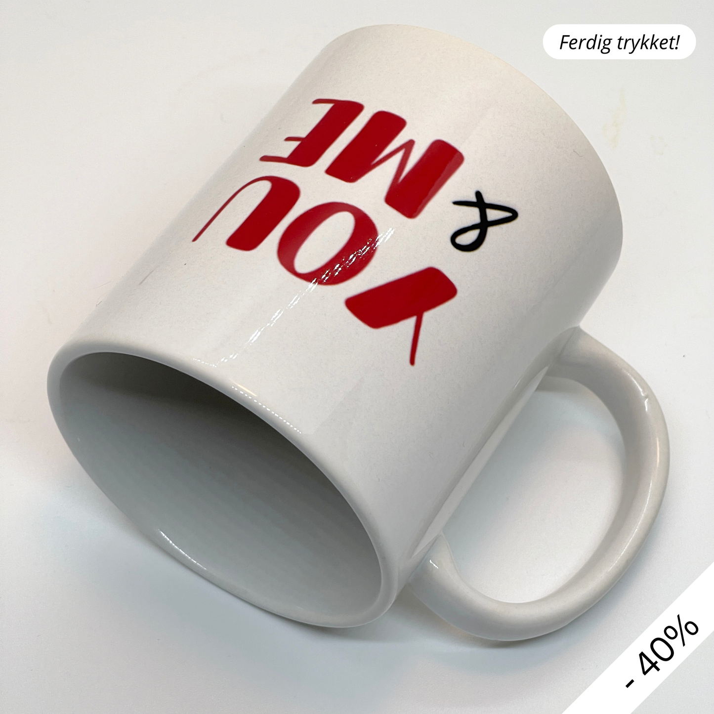 Krus i keramikk med teksten "YOU & ME" og en dristig typografi med et rødt fingeravtrykk-hjerte.
